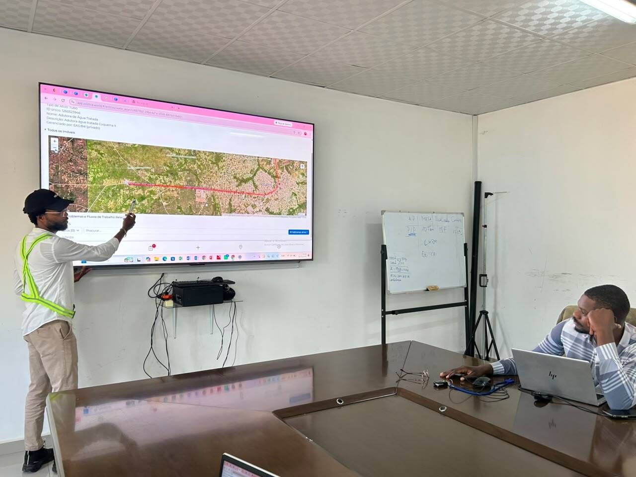 A team member reviews a mapped water pipeline in mWater with utility staff in Bié, Angola
